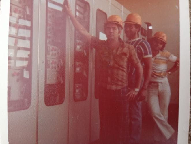 Equipe diante de um painel elétrico, em foto de arquivo da EMR
